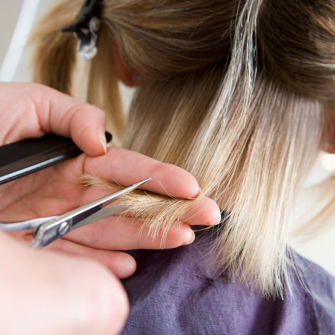 A blonde woman getting a haircut.