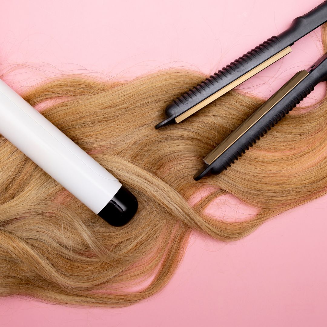 Curling iron and hair straightener on top of blonde hair extensions. 